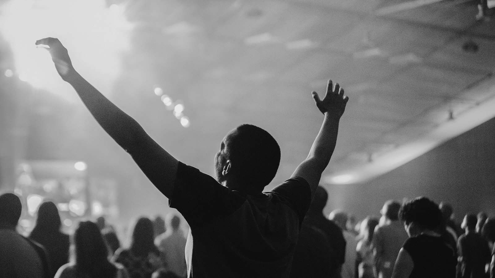 I Get Backing lyrics — worshipper with arms raised toward a bright stage light